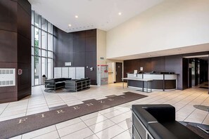 A modern hotel lobby with a reception desk, seating area, and a large window. - Perfect Vancouver Getaway Central 2BR/2BA+Sofa Bed (Vancouver)