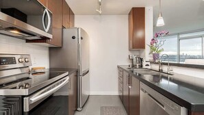 Una cocina moderna con electrodomésticos de acero inoxidable, armarios de madera y vistas a la ciudad.