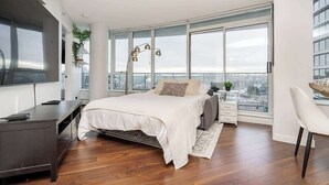 Un dormitorio moderno con cama, mesita de noche y un ventanal grande.
