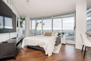 A modern bedroom with a bed, bedside table, and a large window. - Perfect Vancouver Getaway Central 2BR/2BA+Sofa Bed (Vancouver)