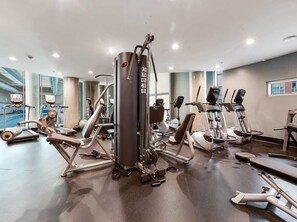 A gym with various exercise machines, including a central piece of equipment with multiple handles and a weight stack. - Perfect Vancouver Getaway Central 2BR/2BA+Sofa Bed (Vancouver)