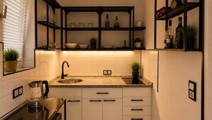 Una cocina compacta con lavamanos, encimera y estantes empotrados.