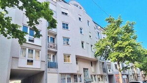 Un edificio residencial de varios pisos con balcones y un estacionamiento con varios automóviles.