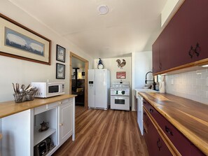 Una cucina compatta con forno a microonde, frigorifero, forno e piano di lavoro in legno.