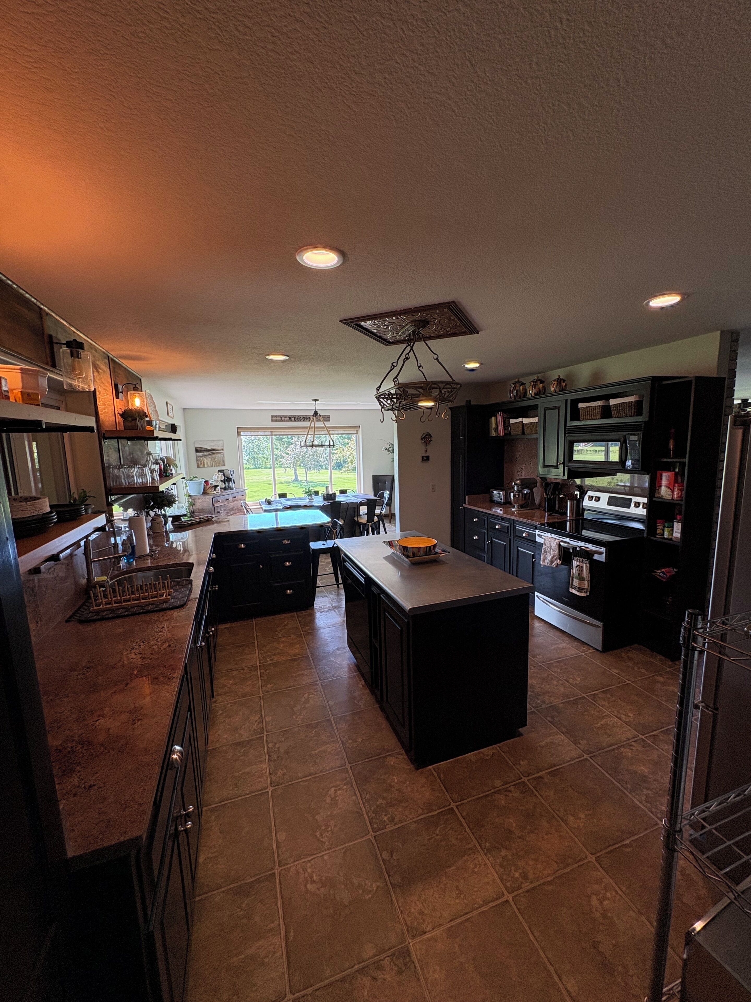 Una cocina amplia con una isla central, muebles oscuros y vistas al exterior.