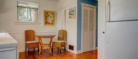 Una cocina con una mesa de comedor y sillas, piso de madera, un refrigerador blanco y una pared de acento azul.