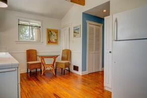 A kitchen with a dining table and chairs, wooden flooring, a white refrigerator, and a blue accent wall. - Hidden Gem: Private 650sq ft Studio, Free Parking, Pool, Walkable, Near Downtown (St. Augustine)