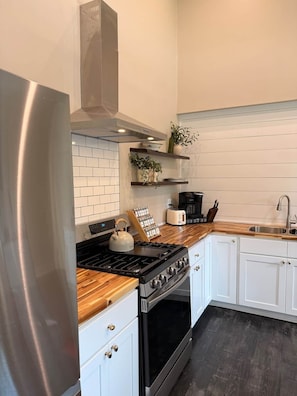 A modern kitchen with white cabinetry, a stainless steel refrigerator, a gas stove, and a built-in oven.