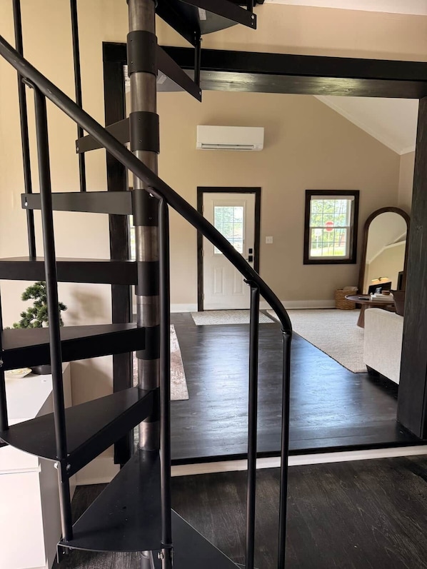 A modern interior with a dark wood staircase leading to a living area.
