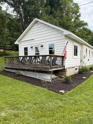 A white single-story house with a wooden deck and a small porch.