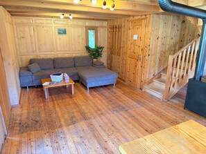 Un intérieur en bois comprenant un canapé, une petite table, un escalier et une plante.