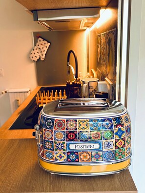 A kitchen with a colorful Positano toaster on the counter, a sink, and a wall-mounted oven. - Nice Studio "Azure Escape" (Nice)
