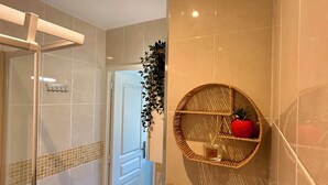 A bathroom with a glass shower enclosure, a toilet, a sink, and a wall-mounted shelf with a decorative item. - Nice Studio "Azure Escape" (Nice)