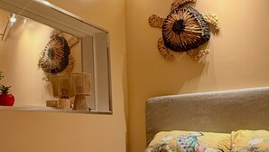 A bed with striped pillows, a headboard, a wall decoration, and a mirror. - Nice Studio "Azure Escape" (Nice)