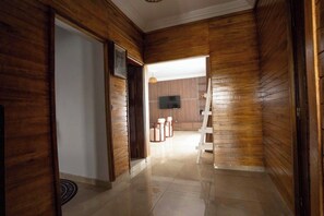 A hallway with wooden paneling, a white door, and a television mounted on the wall. - Tita, T2 piscine & charme africain (Abidjan)