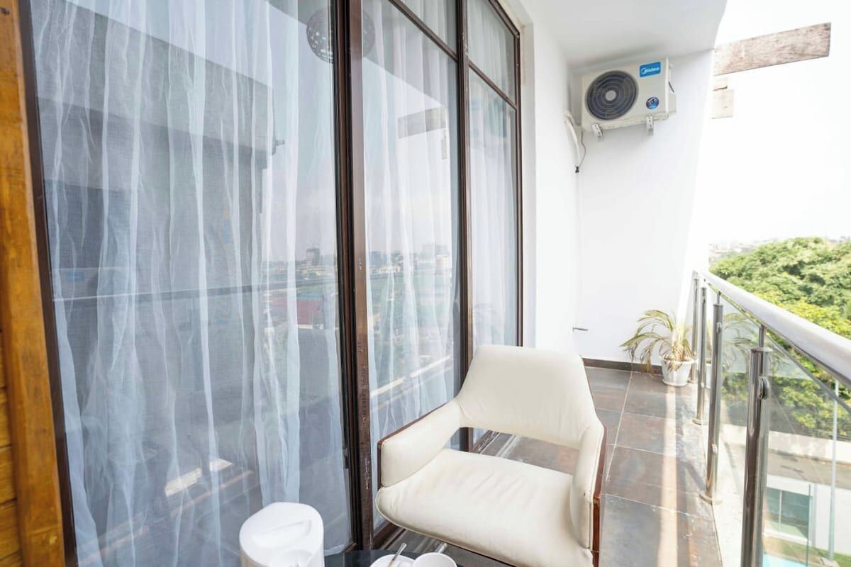 A balcony with a chair, a small table, and a potted plant.