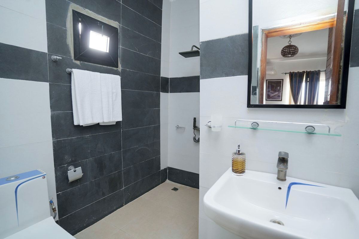 A bathroom with a white sink, a mirror, and a towel hanging on the wall.