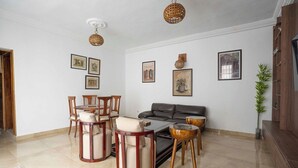 Una sala de estar con sofá, sillas, una mesa de centro y cuadros en la pared.
