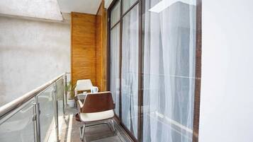 Ein Balkon mit einem Stuhl, einem kleinen Tisch und einem Blumentopf.