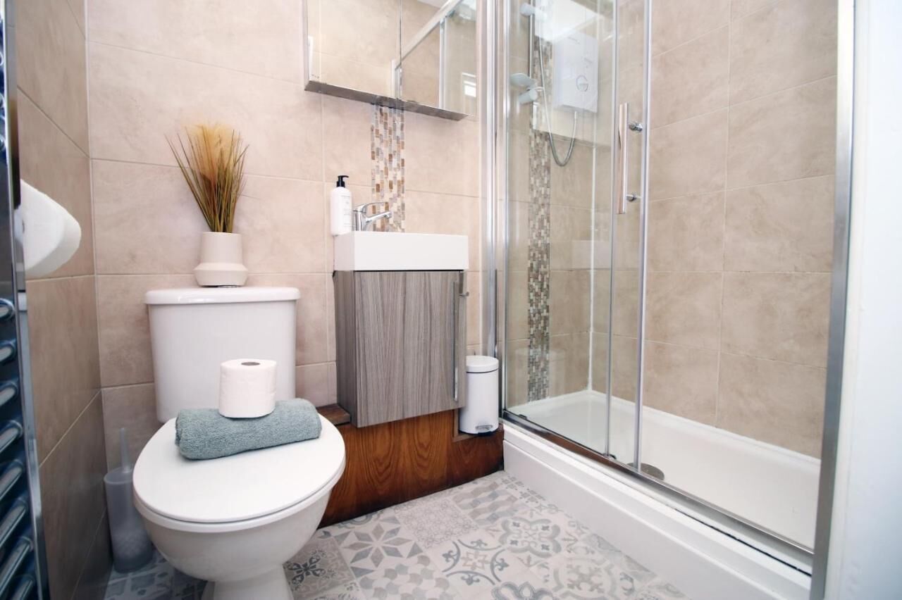 Een moderne badkamer met toilet, wastafel en douche.