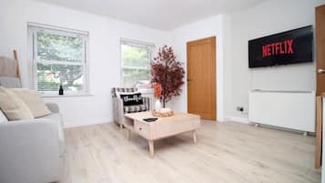 Un salon moderne avec un canapé, une table basse, un téléviseur et une porte.