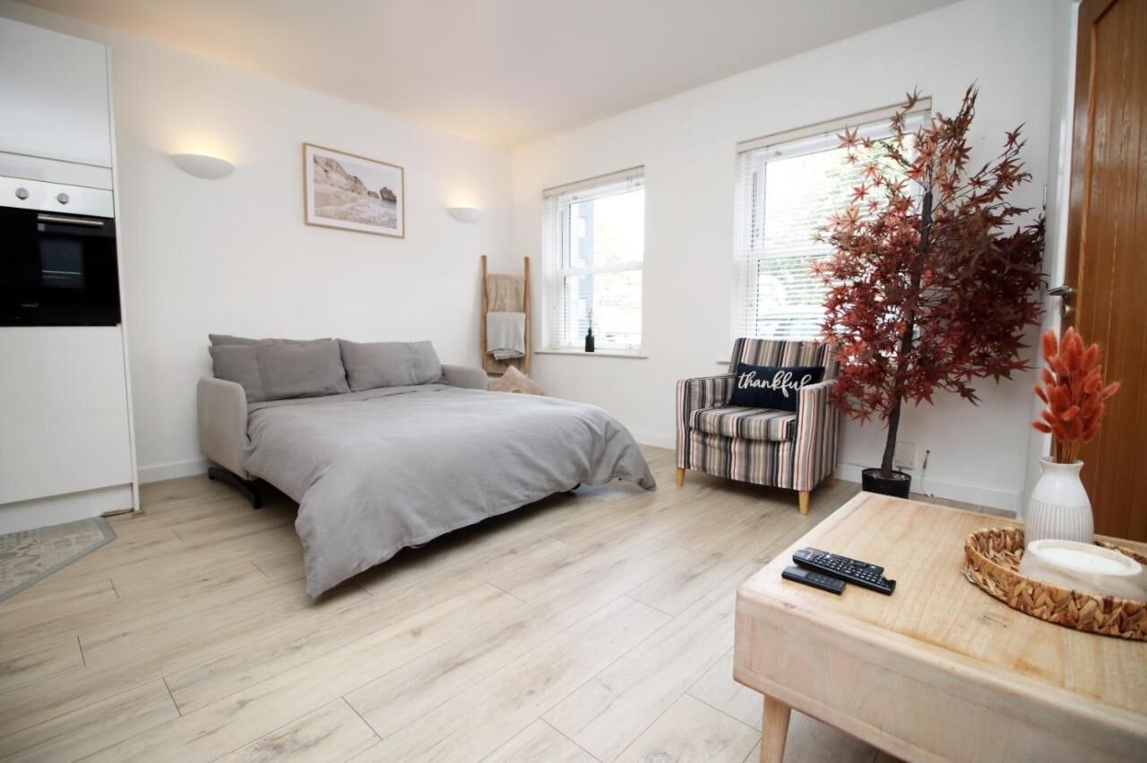 Une chambre à coucher avec un lit, une chaise, une petite table, une plante en pot et une fenêtre.