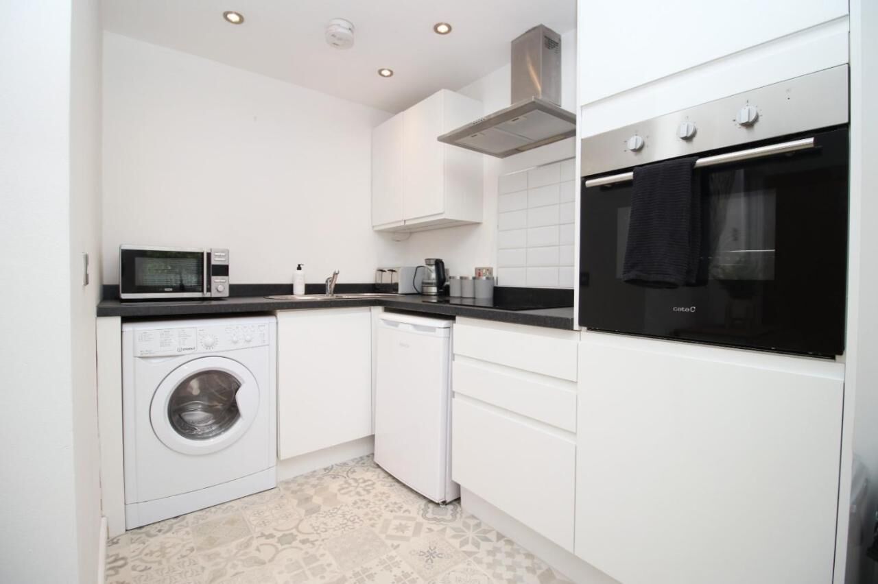 A compact kitchen with a washing machine, dishwasher, microwave, and oven.