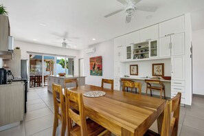 Eine moderne Küche mit weißen Schränken, einem Holztisch und einem Deckenventilator.