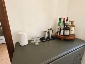 A bar area with a bar counter, a white bar towel, a set of bar tools, and various bottles of liquor. - Camp Coronado- Classic Summer House in the Village of Jamestown (Jamestown)
