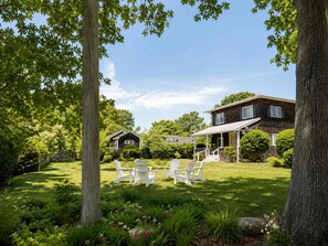 A two-story house with a covered porch and a lawn with white chairs. - Camp Coronado- Classic Summer House in the Village of Jamestown (Jamestown)