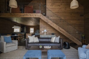 Ein geräumiger Wohnbereich mit einer großen Holztreppe, einer Couch und einem Essbereich.