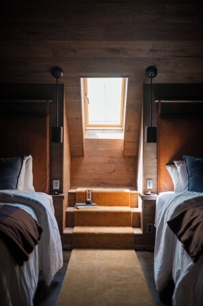 Ein Schlafzimmer mit zwei Betten, einem Oberlicht und einer kleinen Sitzecke.