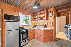 A compact kitchen with a refrigerator, stove, oven, wooden cabinets, and a microwave. - Hideaway at Elm Grove: Cabin - Shop - Pool Table - Fire Pit (Valley View)