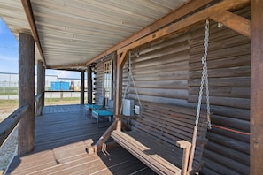 Una terraza cubierta de madera con un banco y una mesa, con vistas a una zona industrial.