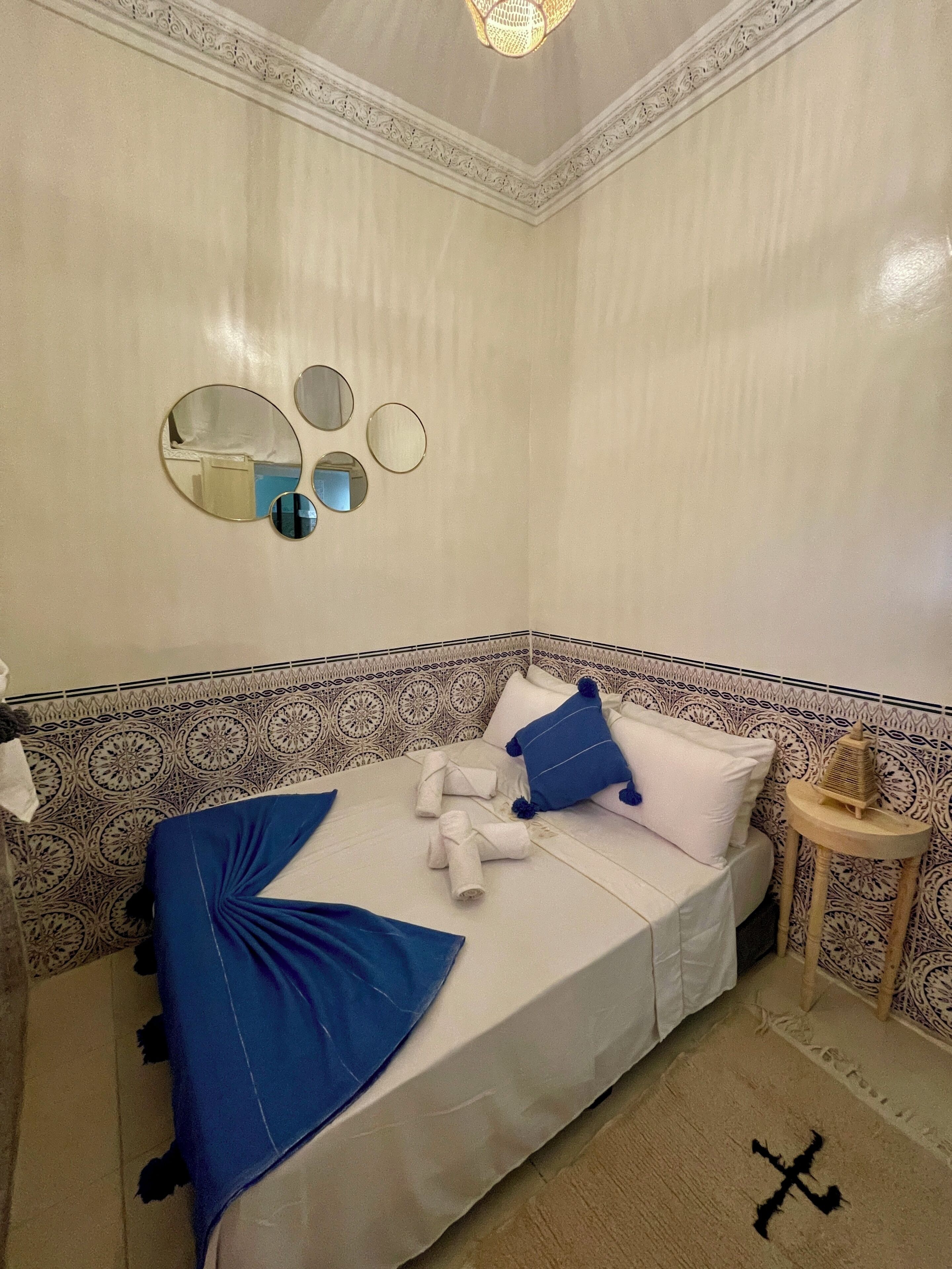 A room with a bed, a bedside table, and a wall with decorative patterns.