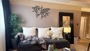 Un dormitorio con cama, un cuadro de un mapa, una planta en maceta, una lámpara y una maleta.