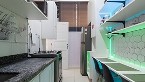 A modern kitchen with a central island, white cabinets, and a green countertop. - Suíte Ampla Augusta Paulista Frei Caneca (São Paulo)