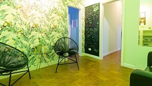 A room with a wooden floor, a chair, a door, and a wall with a leafy pattern. - Suíte Ampla Augusta Paulista Frei Caneca (São Paulo)