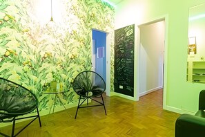 A room with a wooden floor, a chair, a door, and a wall with a leafy pattern. - Suíte Ampla Augusta Paulista Frei Caneca (São Paulo)