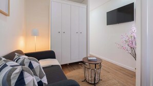A modern room with a sofa, a wardrobe, a TV, and a small table with a book. - 3 Apartments with Swimming Pool by HostWise (Moreira)