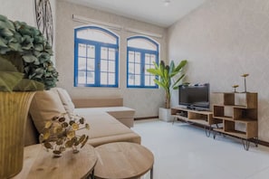 Ett modernt vardagsrum med en soffa, en tv och en växt.