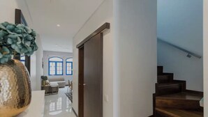 A modern interior with a staircase, a dining area, and a hallway leading to a room with a door. - Tagus View Penthouse · Triplex with Private Terrace (Lisboa)