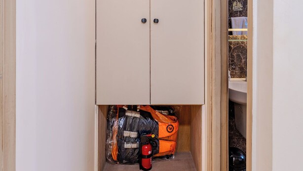 A storage cabinet with a fire extinguisher and a rolled-up item inside. - Prince Anoush Dahabiya 3 Nights (Luxor)
