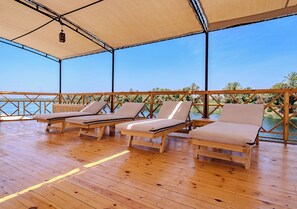 Un espacio al aire libre cubierto con suelo de madera y tres sillones.