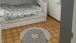 Habitación con literas, ventilador de techo, aire acondicionado, alfombra estampada y piso de baldosas.