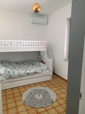 A bunk bed room with a ceiling fan, an air conditioner, a patterned rug, and a tiled floor. - Spacious 4-bed house in Archi, Italy-AC and fitness room sleeps 12 private pool (Archi)