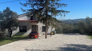 Una casa con camino de entrada de grava, un coche aparcado y un patio cercado.