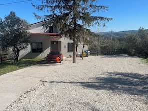 A house with a gravel driveway, a parked car, and a fenced yard. - Spacious 4-bed house in Archi, Italy-AC and fitness room sleeps 12 private pool (Archi)
