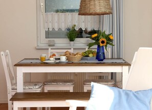 Ein Frühstückstisch mit Eiern, Toast und Obst, eine Vase mit Sonnenblumen und eine Korbtellerlampe.