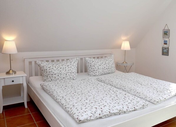 A white bed with floral bedding, two bedside lamps, and a white nightstand.